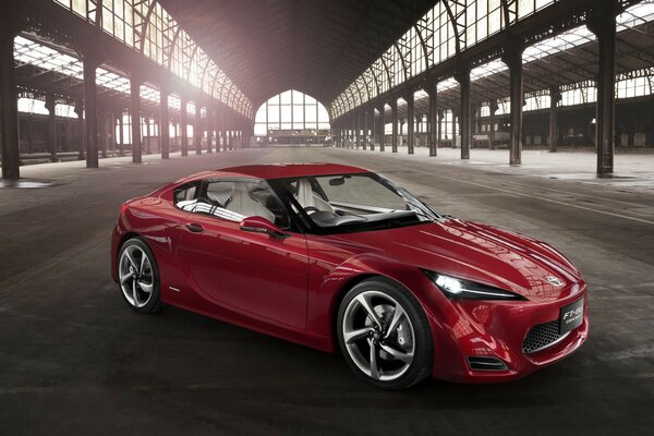 Red Toyota in an empty hangar