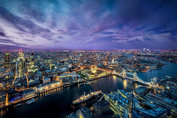 A ship sails on the Thames at night