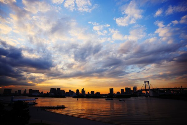 A bridge by the sea against the background of clouds and sunset