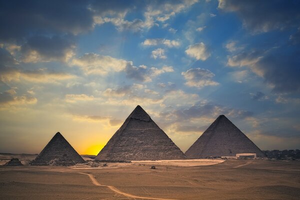 Pyramides égyptiennes dans le désert sur fond de coucher de soleil 