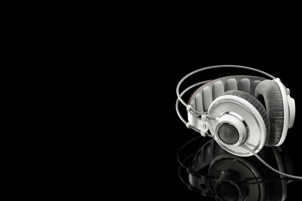 White headphones on a mirror surface and a black background