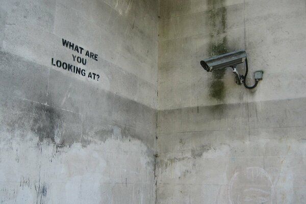 An inscription on a concrete wall with a video surveillance camera