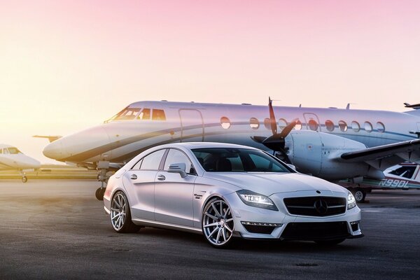 A private plane is parked next to a foreign car