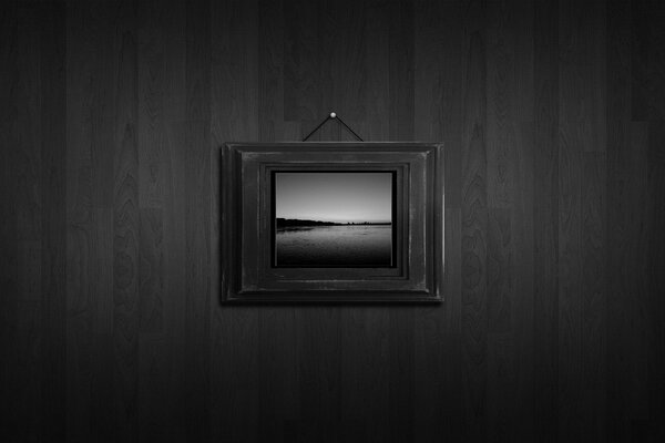 A picture hung on a nail on a black and white background