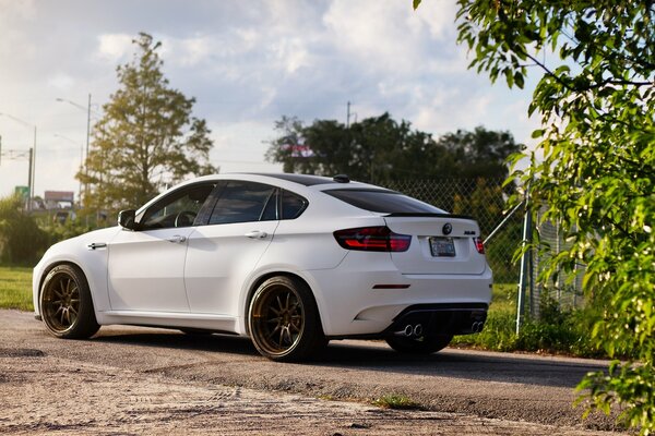 White BMW on the road rear view near the fence