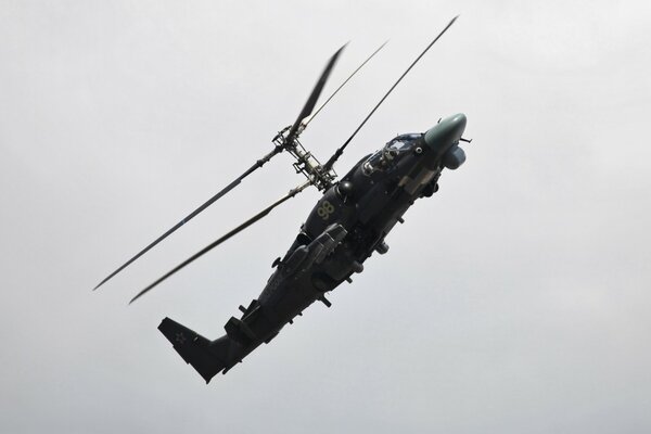 A military helicopter performs an aerobatic figure