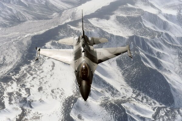 Militärflugzeug fliegt über schneebedeckte Berge