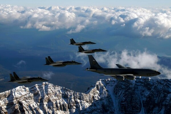 Planes fly in the clouds over the mountains