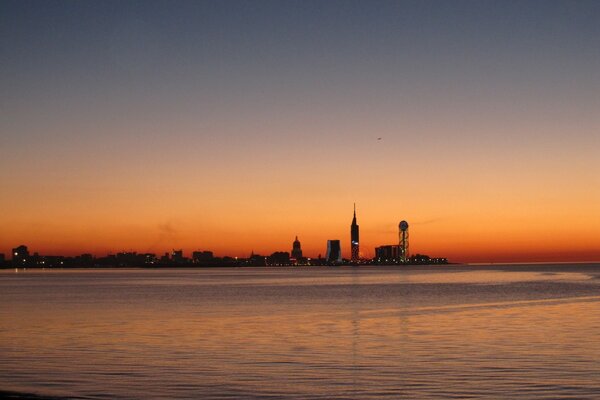 A beautiful city in the distance of the sea on the background of sunset