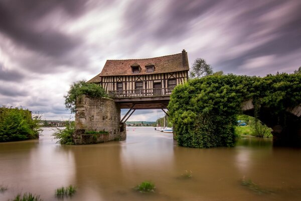 The house is hanging on a broken bridge over the water