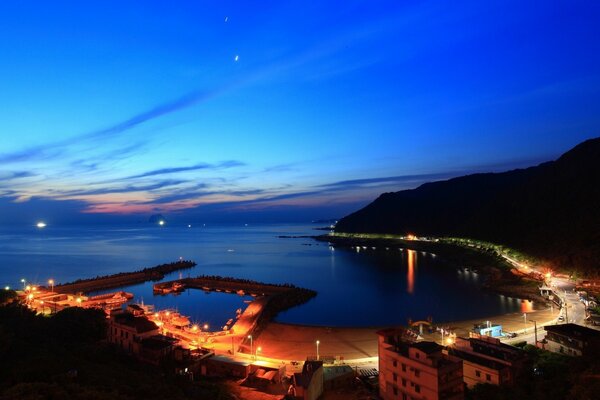 Ville de nuit au bord de la mer. Coucher du soleil