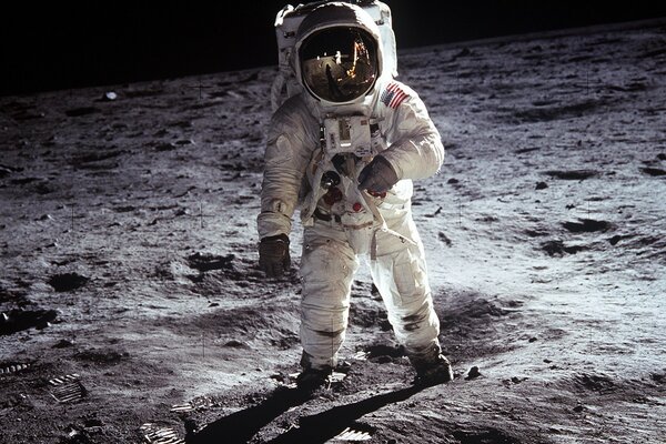 An astronaut in a spacesuit walks on the surface of the Moon