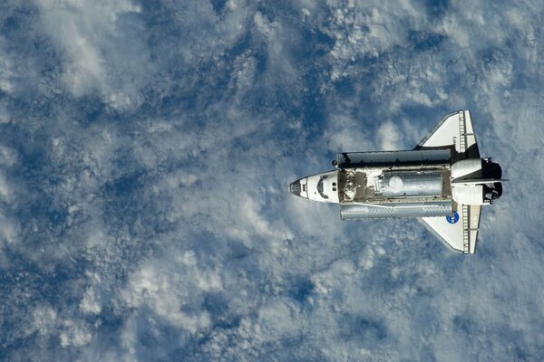 Space shuttle on the background of clouds and earth