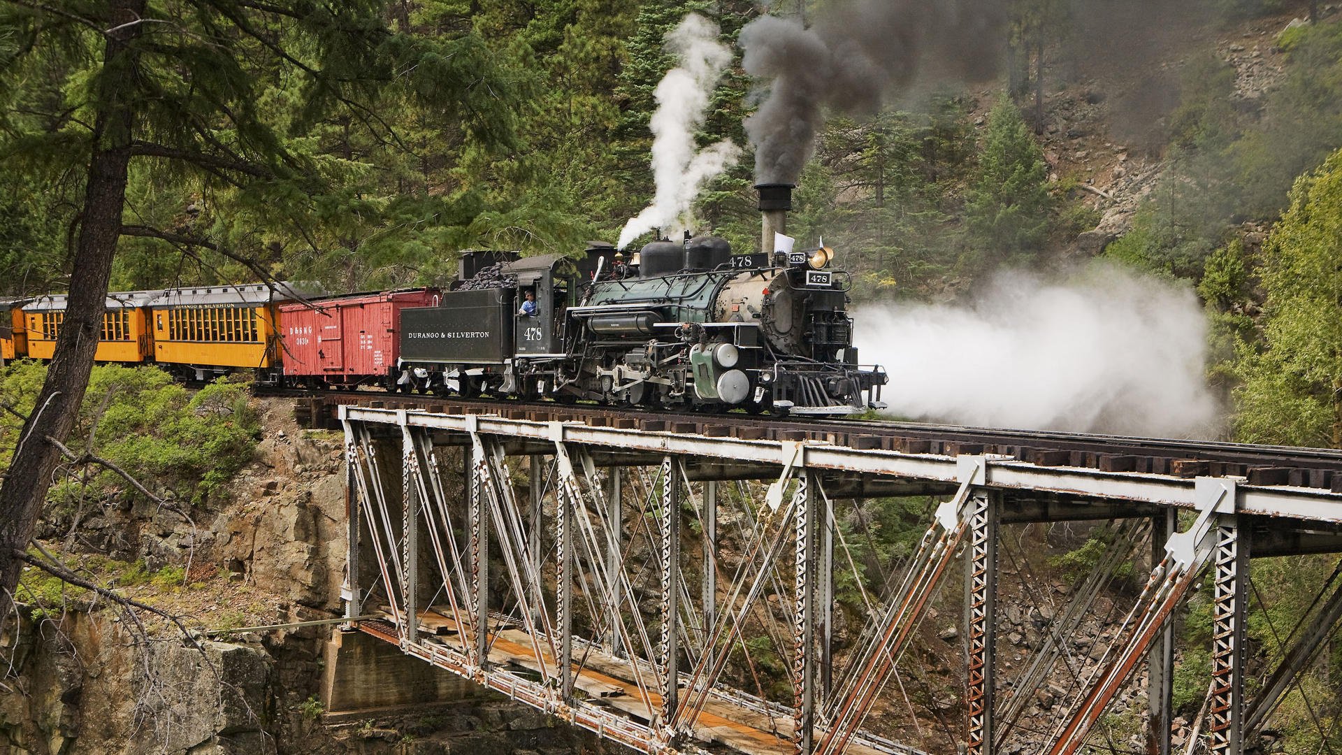 across the bridge the engine pair composition transport forest greens smoke stone mountains rocks cars train transport