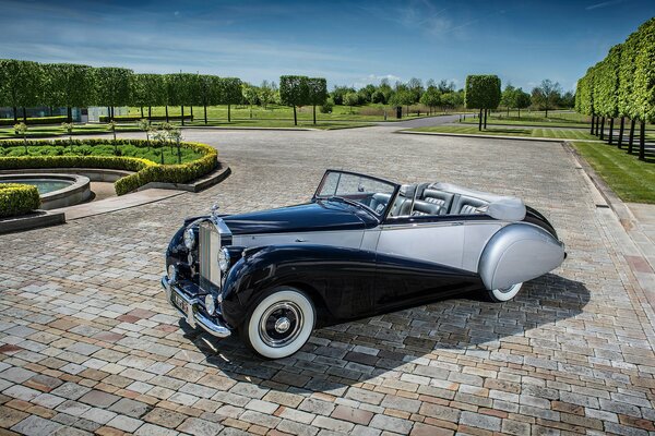 Silver Rolls-Royce in the park on the cobblestones