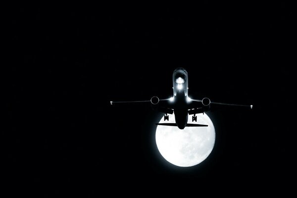 Night flight of an airplane on the background of the moon