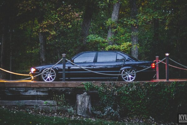 BMW e38 740il black on the bridge with lights on side view