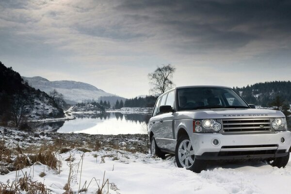 Land rover bianco nel paesaggio invernale vicino al lago