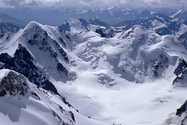 Snow - capped mountain peaks , cloudy sky