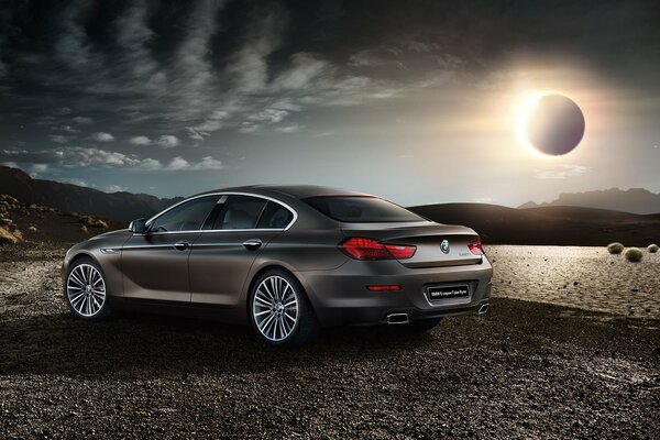 BMW gris mate en el fondo del Eclipse solar