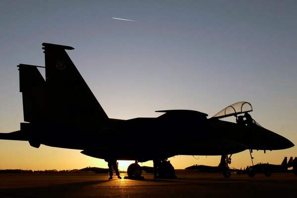 An f-15 fighter jet at the base during sunset