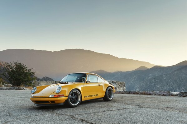 Yellow Porsche on the background of beautiful mountains