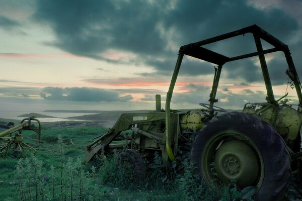 An abandoned tractor in the woods , in the dark