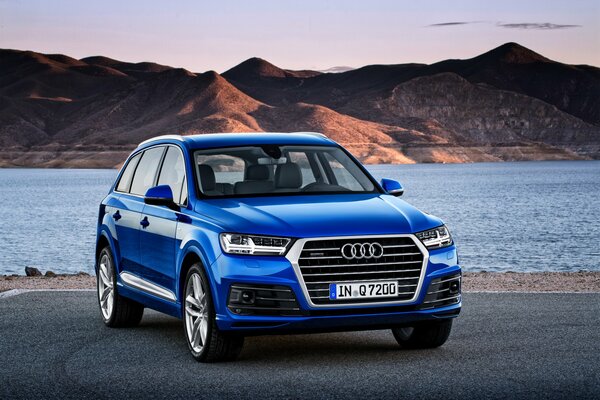 Leuchtend blauer Audi q7 2015 im Hintergrund eines Gebirgstausees