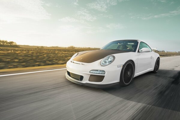 Weißer Porsche mit schwarzer Motorhaube auf der Strecke