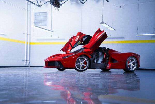 A red supercar stands in the middle of a bright hall