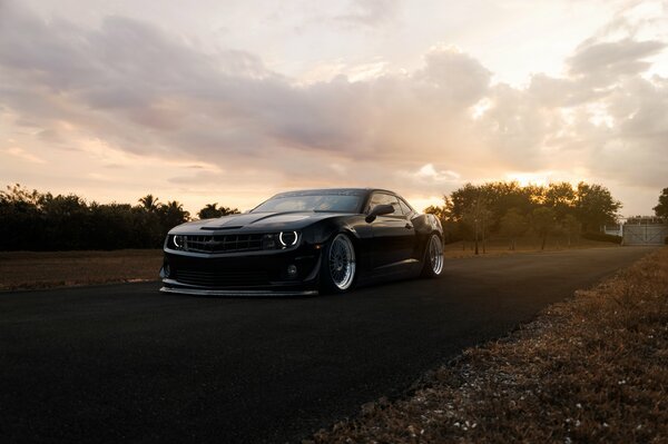 The car is black on the background of an autumn forest