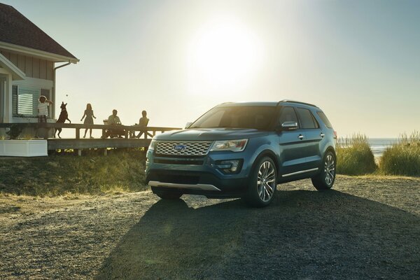 Ford Explorer, iluminado por el sol, de pie cerca de la casa