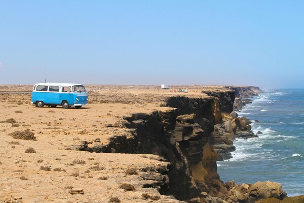 Minibús al pie de la montaña en medio del mar con olas