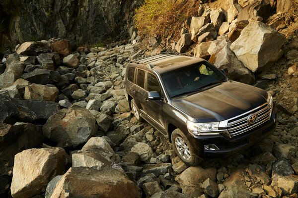 Toyota Land Cruiser en medio de un camino rocoso y montañas