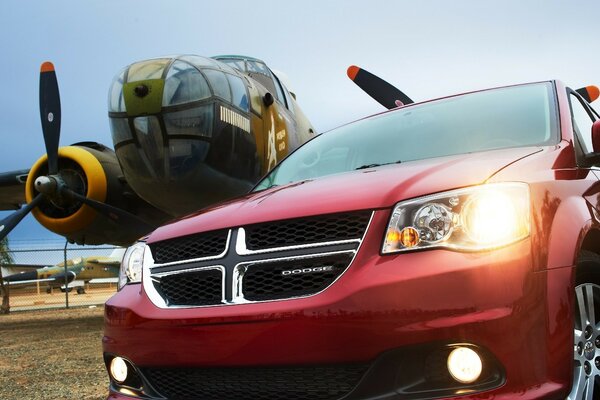 A plane with a propeller and a Dodge car