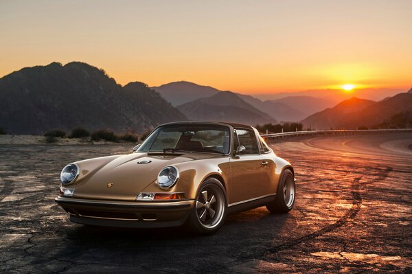 Porsche 911 se tient sur le bord de la route au coucher du soleil