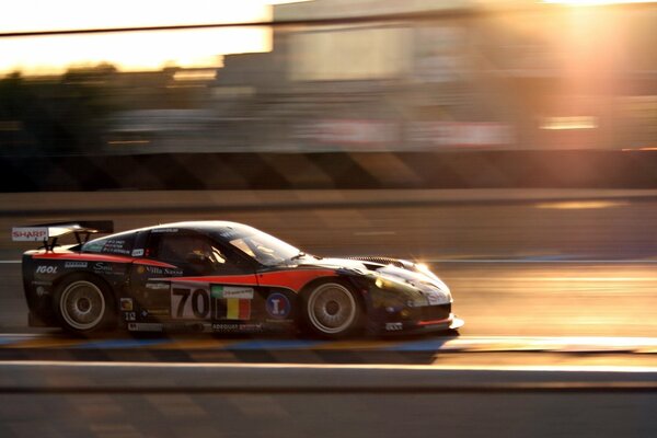 Corvette de alta velocidad en la pista temprano en la mañana. Coche deportivo en el sol naciente