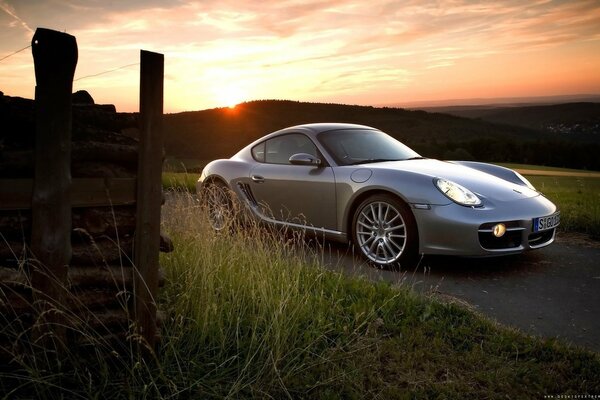 Grauer Porsche Cayman bei Sonnenuntergang