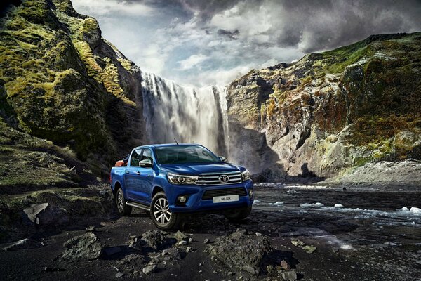 Car blue hatchback Toyota on the background of a waterfall