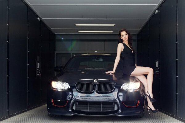 Girl on the hood of a black car in the garage