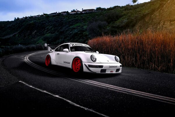 White racing car rides along the road along the mountains