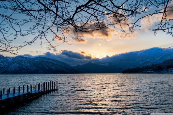 A bridge from the shore to the water where the mountains are far away