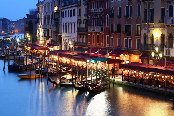 Góndolas en el muelle de Venecia. Italia nocturna, canal iluminado por linternas