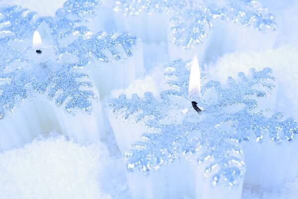 Kerzen in Form von Schneeflocken im Schnee