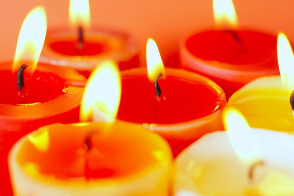 Velas de colores, iluminadas sobre un fondo naranja