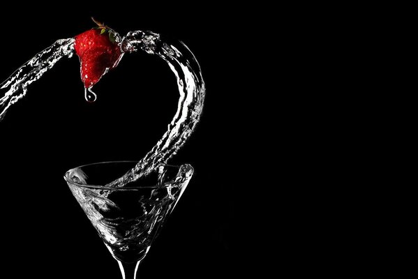 Spruzzata di acqua trasparente da un bicchiere di vino con fragole su sfondo nero