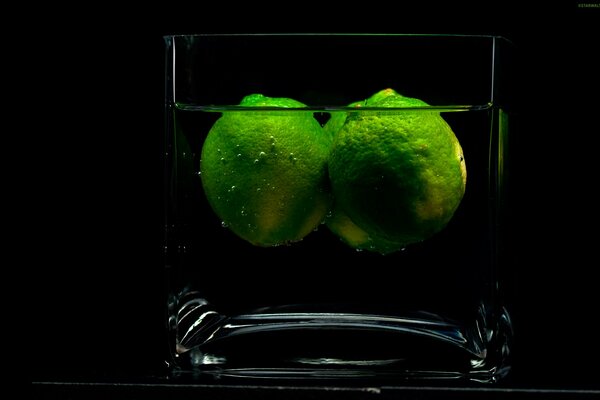 Zwei Limetten in einem Glas auf schwarzem Hintergrund