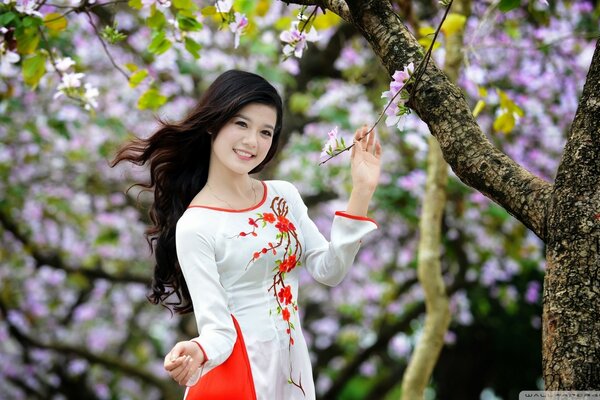 A girl in a red and white dress near beautiful trees