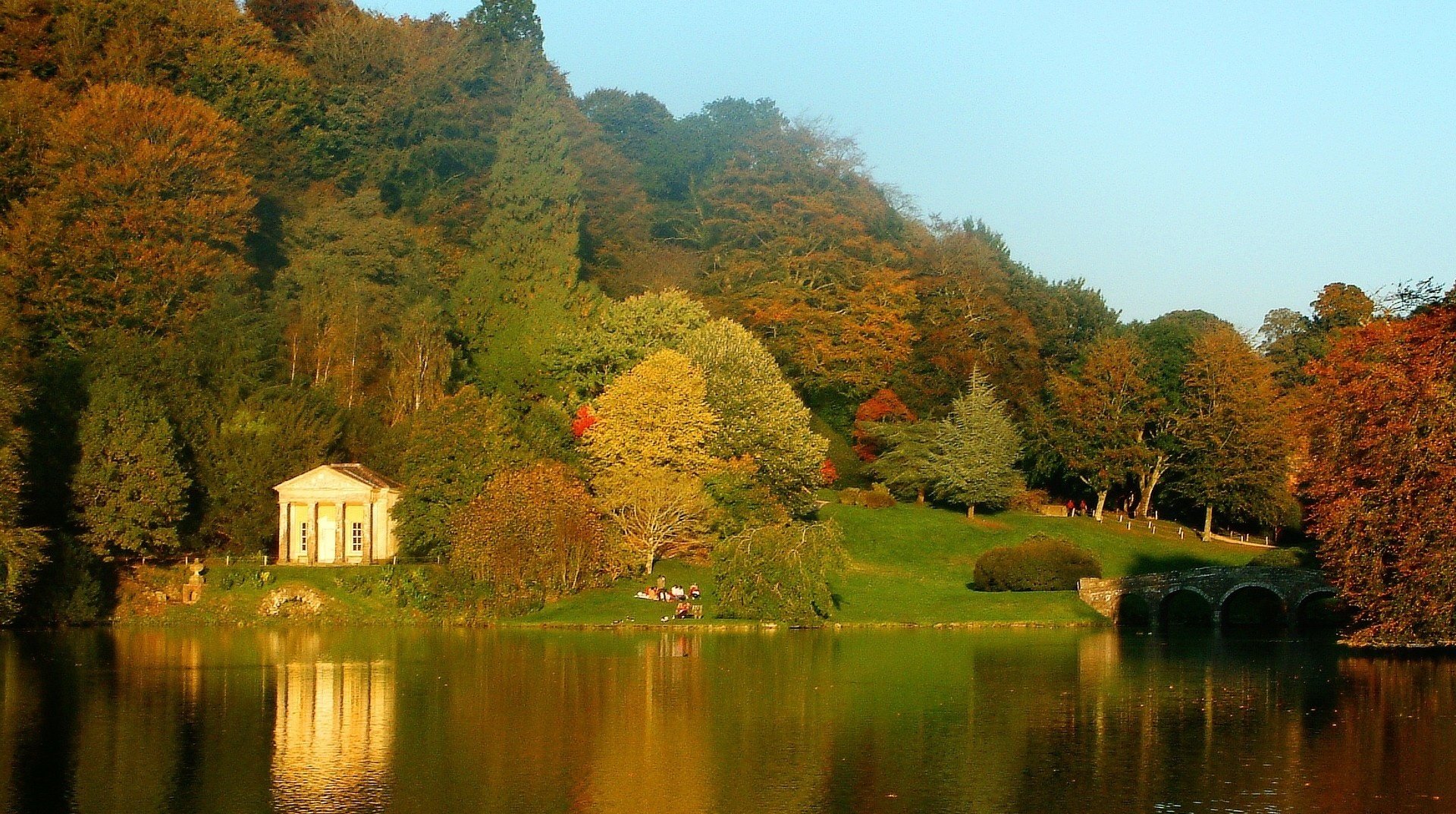 steinbrücke berglandschaft haus am see see haus wald laubfall goldene zeit sommer gelbe blätter herbstfarben glatte oberfläche reflexion grün hügel