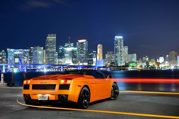 Supercar orange sur fond de Panorama de la ville de nuit